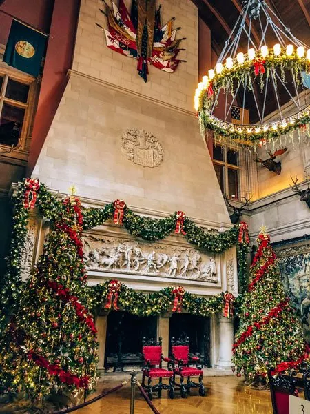 Biltmore Christmas with large stone fireplace decorated with Christmas trees and garland