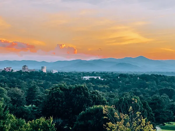 Omni Grove Park Inn Sunset in Asheville NC with pink, orange, yellow and purple sky over Blue Ridge Mountains and Downtown Asheville