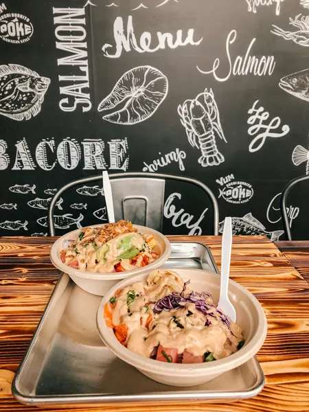 Yum Poke Spot Sushi Asheville with two poke bowls and black wall with fish sketches