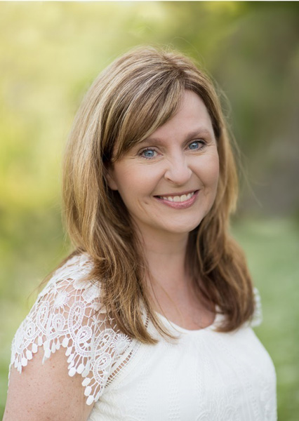 Renea Winchester portrait of white woman with blondish brown just over shoulder-length hair in white shirt with green background