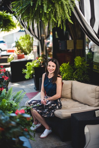 Battery Park Book Exchange Asheville NC outside patio with white woman in a navy blue dress with cat skirt sitting on a couch