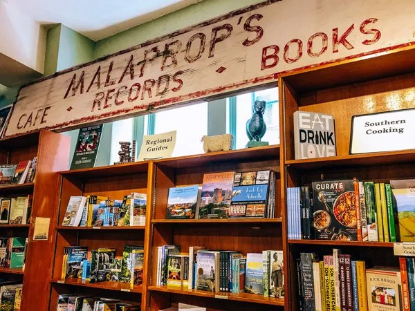 Malaprop's Bookstore/Cafe Asheville, NC picture with Malaprop's sign over wooden bookshelves filled with books