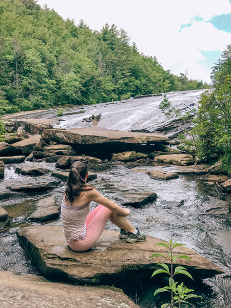 Bridal Veil Falls DuPont Waterfall Hikes with white brunette woman in pink yoga pants sitting on a rock looking at the wide waterfall