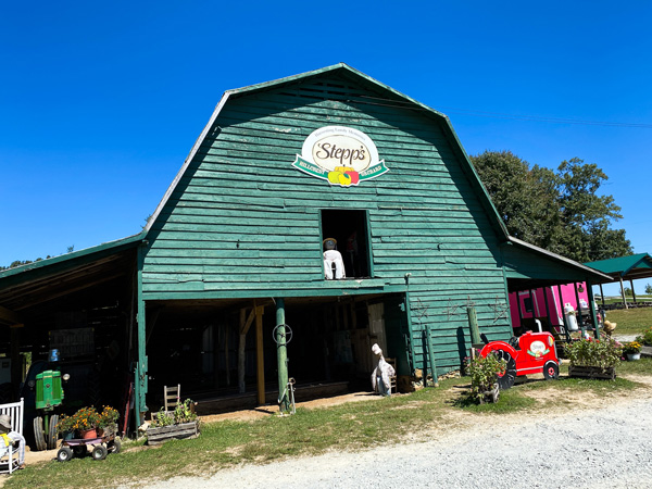 Stepp's Hillcrest Orchard Hendersonville NC green farm store with logo and red tractor out front