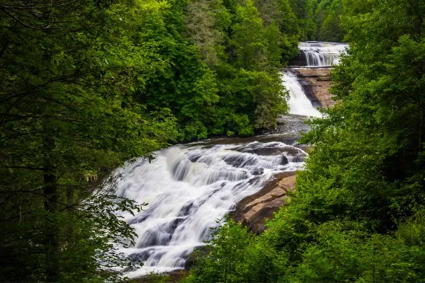Triple Falls at DuPont State Recreational Forest with three tiered waterfall surrounded by green trees