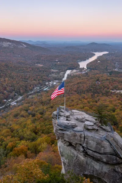 Chimney Rock North Carolina Fall with rock jutting out with American flag and view of Lake Lure
