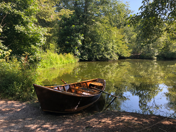 Hiking In Asheville Biltmore Lagoon Trail with brown boat sitting on a lagoon