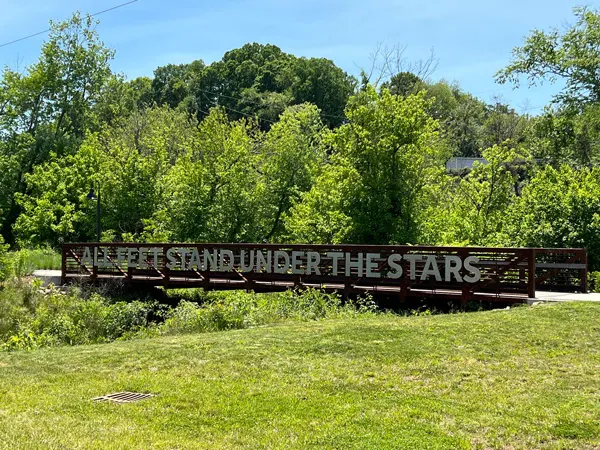 River Arts District Riverwalk Asheville with bridge with phrase that says all feet stand under stars