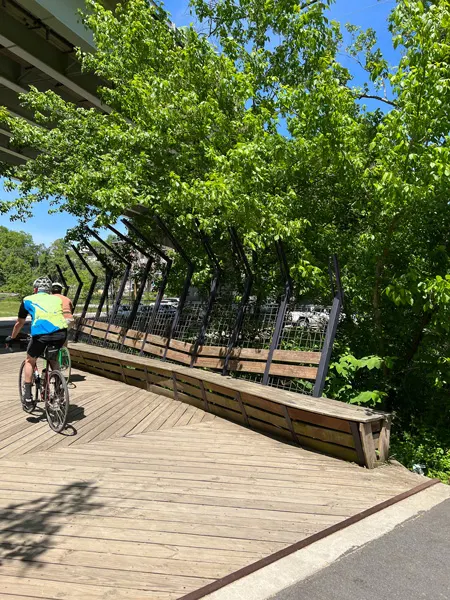 River Arts District Riverwalk Parks Asheville with two bikers on bridge with green trees