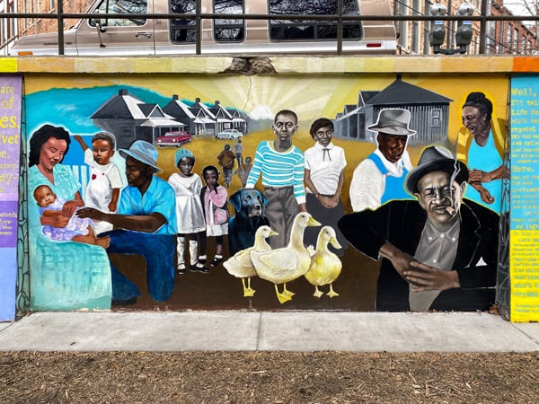 Triangle Park Asheville NC Murals with young and old Black community members with gray houses and yellow ducks