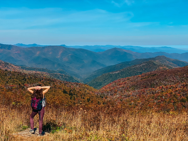 Fall Things To Do In Asheville NC Hiking Art Loeb Trail with brunette white woman with hiking backpack on Art Loeb trail looking at the mountains