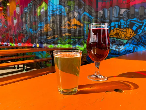 Hi Wire Brewing RAD Beer Garden Asheville with light lager and red cider on orange picnic table surrounded by street art