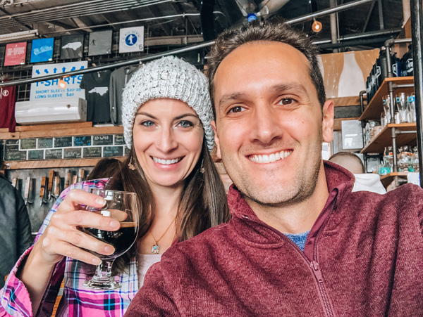 Tom and Christine, a brunette white male and female taking a selfie and holding beer, at Hi-Wire Brewing in Asheville's South Slope