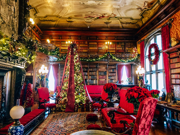 Biltmore at Christmas with picture of Vanderbilt library decorated with Christmas trees and garland