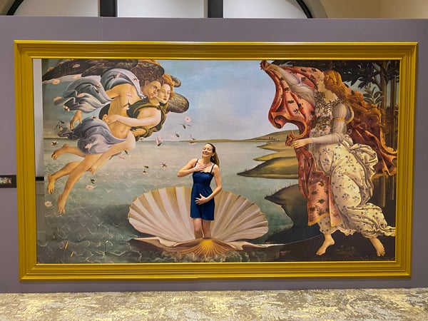 Italian Renaissance Alive at Biltmore Estate in Asheville with white brunette woman in blue dress standing in picture frame with painting of shell and people