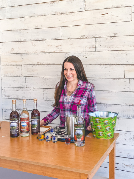 Adam Dalton Distillery Asheville with white brunette woman in pink plaid shirt making a cocktail with Dalton rum and juices