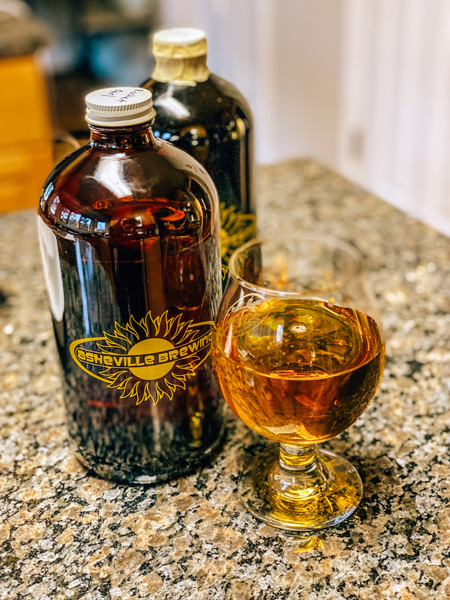 Asheville Brewing takeout growlers with glass of lager beer