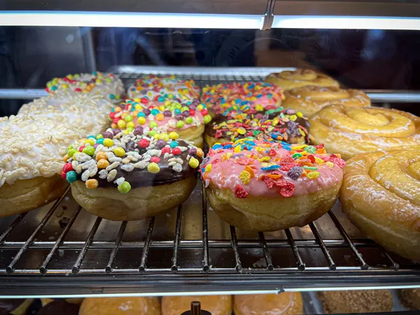 Avas Donuts in Biltmore Town Park Square in Asheville, NC with four columns of different glazed and sprinkled donuts in glass viewing display on wire rack