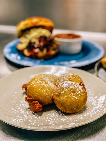 Deep Fried Oreos Big South Kitchen BBQ with powdered sugar and pulled pork sandwich in the background