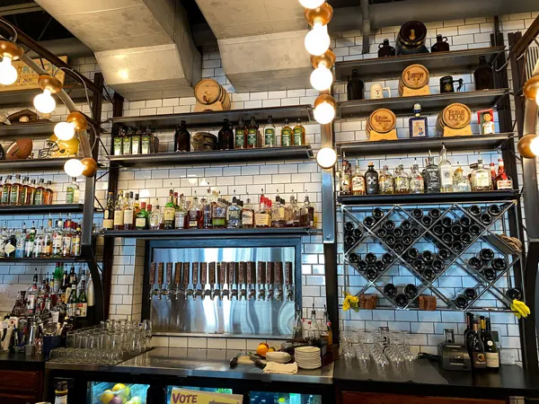 Rye Knot Bar Asheville NC with white tiled backsplash and brown shelves filled with liquor over and around beer taps