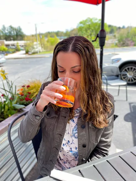 Rye Knot North Asheville Restaurant with white brunette woman drinking an old fashioned cocktail outside at black table