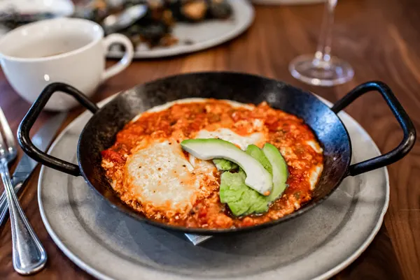 Takeout in Asheville NC Tupelo Honey Southern Shakshuka in a black skillet with avocado