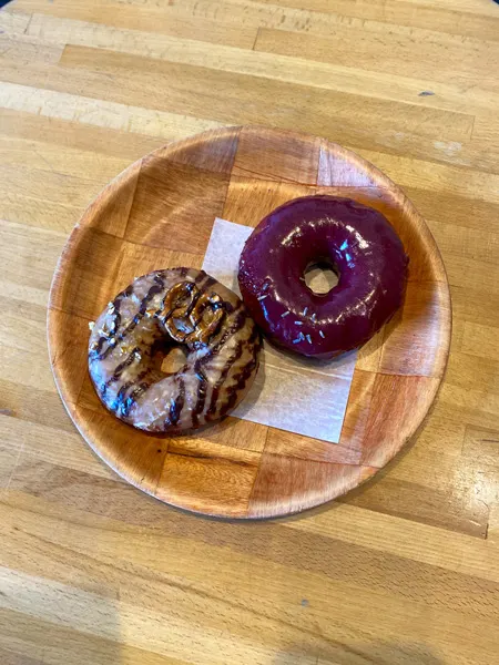 Vortex Doughnuts vegan donuts Asheville shop with red glaze and brown glazed donuts on brown plate on a table