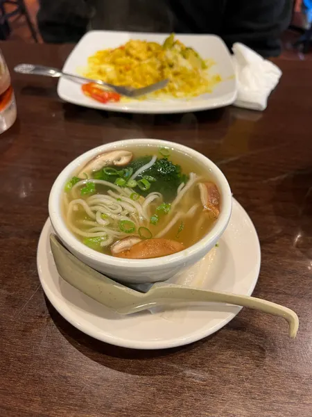 Blue Dream Curry House Asheville NC noodle soup with mushrooms and scallions in white bowl on brown table