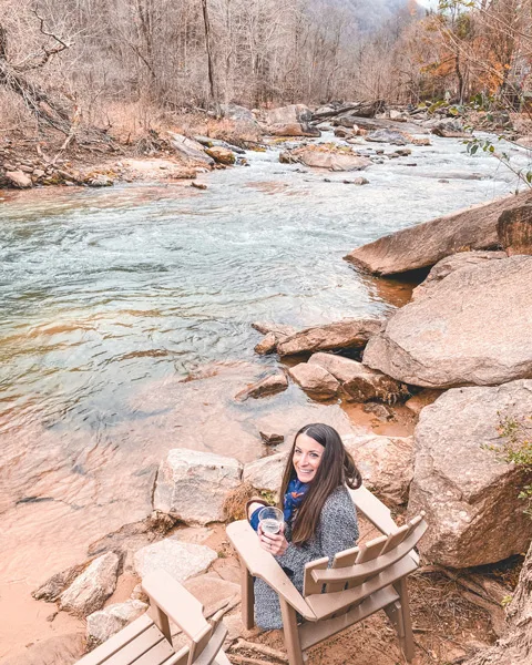 Hickory Nut Gorge Brewery Near Wildcat Rock Trail with brunette white woman sitting in a chair and drinking an amber beer