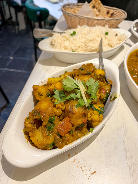 Mehfil Indian food in Asheville, NC with dish of aloo gobi - cauliflower, potatoes, and cilantro - with rice on table