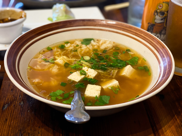 Ginger soup with tofu and cilantro in white bowl with red rim design at Thai Pearl in West Asheville