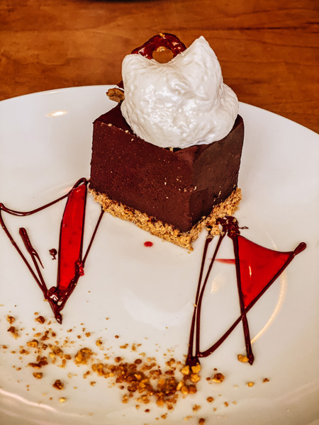 Vegan Dessert Plant Asheville chocolate cake on crust with whipped cream, red sauce, and nuts