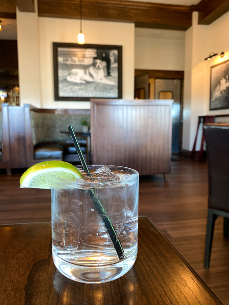 Biltmore Estate Cedrics Tavern gin and tonic on brown table with black and white photo of Cedric the St Bernard in the background