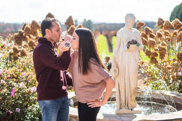 Burntshirt Vineyards Hendersonville, North Carolina with brunette white male and female drinking red and white wine in front of a fountain