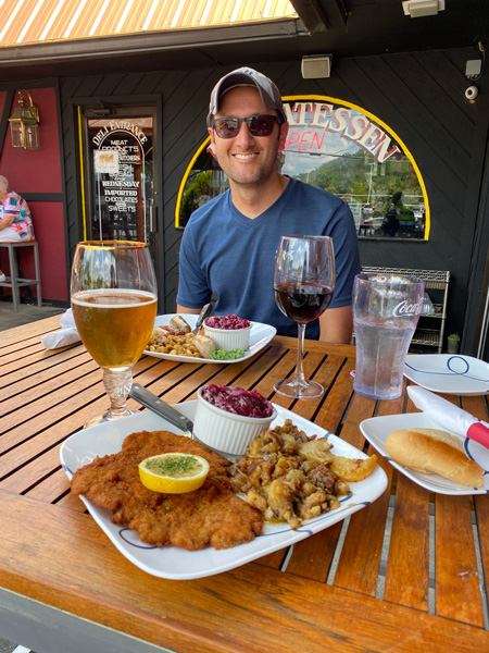 Haus Heidelberg German Restaurant Hendersonville NC white brunette male with two plates of potatoes, meat, beer, and white