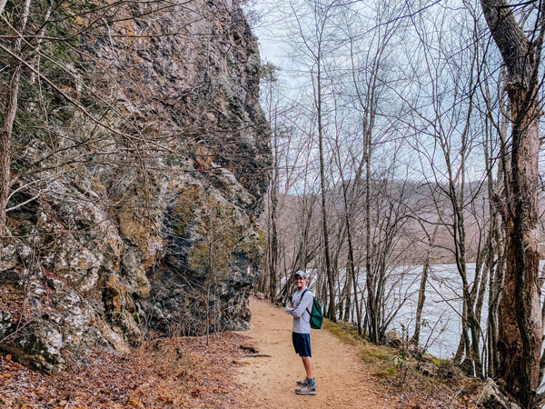 Appalachian Trail Lover's Leap Loop Hot Springs NC with white white brunette male with green backpack and hat standing in front of a rock and French Broad River