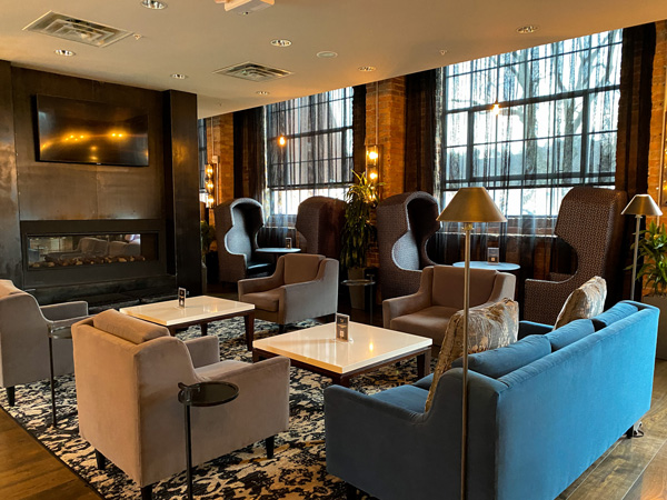 Bar Area The Foundry Hotel Asheville NC with couches and chairs with white tables and sleek gray fireplace