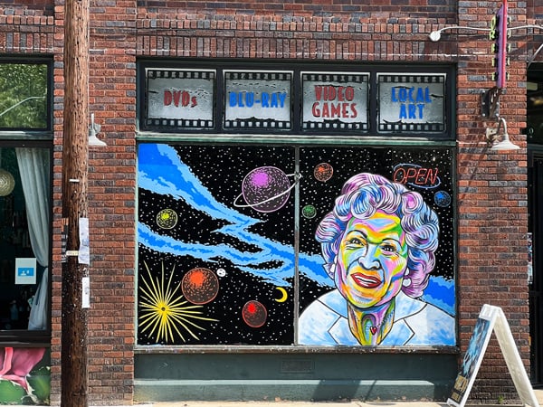 Rainbow colored portrait of Betty White and solar system mural on window by artist Austen Mikulka on Orbit DVD in Asheville