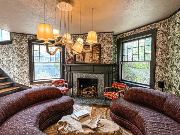 Blind Tiger Asheville Bed and Breakfast Living Room with fun multiple lamp chandelier, red couches and green fireplace