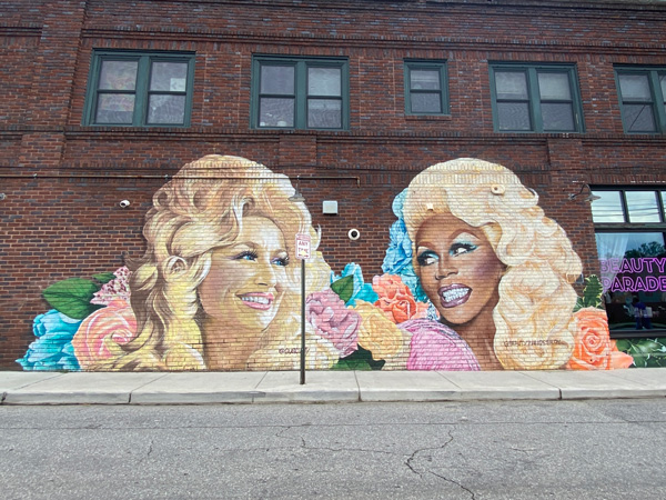 Dolly Parton and RuPaul Mural in West Asheville NC with portrait of their heads and blue and pink flowers