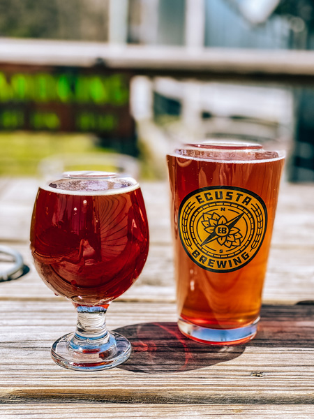 Ecusta Brewing Company Brevard NC with amber colored beer and mixed berry cider in Ecusta beer glass