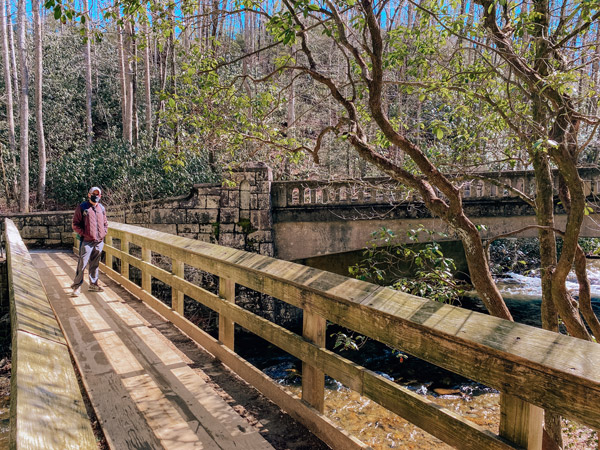 Entrance to Moore Cove Falls with brunette white male standing on wooden bridge