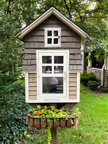 Free Little Library with wooden outdoor miniature house holding books with windows in Historic Montford In Asheville, NC