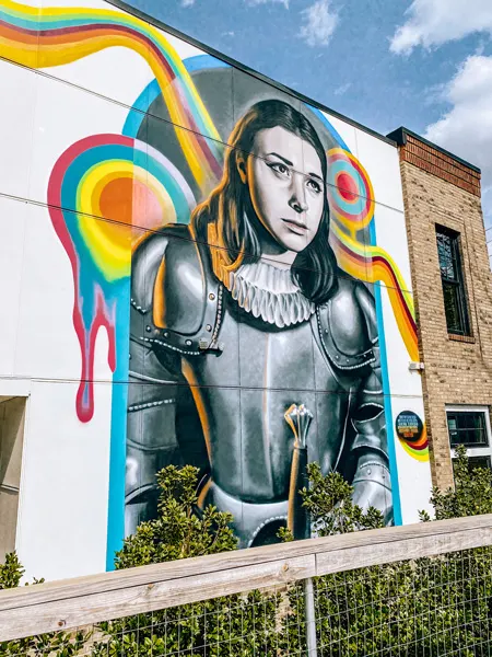 Joan of Arc Ella Mural West Asheville with young woman with shoulder length hair in suit of armor