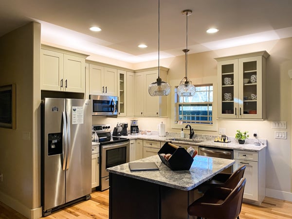 Kitchen Asheville Cottages with fridge, island, gray granite counter tops, and white cabinets