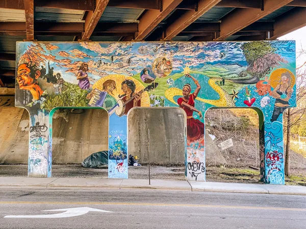 Lexington Gateway Mural Asheville NC with colorful portraits under a highway bridge on columns 