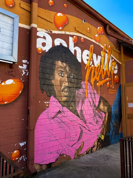 Lionel Richie Mural by Gus Cutty The Orange Peel Asheville with Richie, a Black man, wearing a hot pink shirt and jeans
