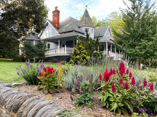 Montford Neighborhood In Asheville NC with purple and blue older Victorian home with pink flowers out front