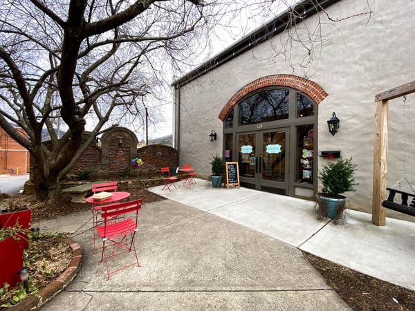 Sassafras On Sutton Black Mountain NC bookstore white building with swing and patio with small red chairs and tables