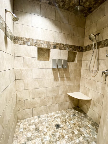 Shower Asheville Cottages with three shower heads one of which is rain shower and tan and brown tile